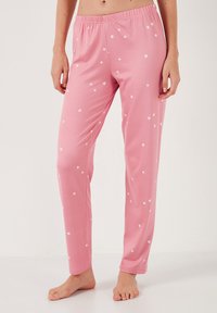 Pantalones de pijama rosa hechos de una tela suave, con un corte relajado y una cinturilla elástica, decorados con estampados de estrellas blancas.