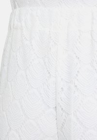 White lace fabric featuring a textured leaf pattern with openwork details, structured with an elastic waistband for comfort.