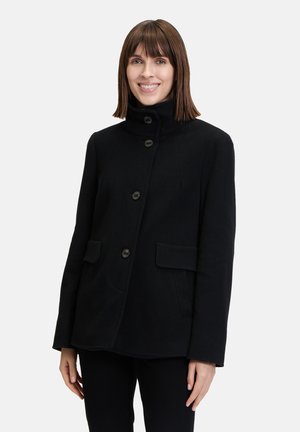 Zwarte wollen jas met een hoge kraag, vijf knoopsluitingen en twee voorzakken. Heeft een gestructureerd ontwerp en een gladde textuur.