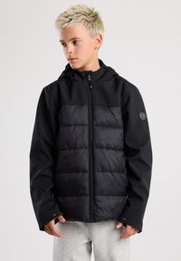 Musta puhvijakki hupulla, jossa on tikattu muotoilu edessä ja sileät sivut, vetoketjukiinnitys ja logo-aksentti hihassa.