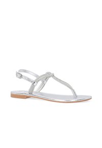 Sølvfarvede flade sandaler med fletede stropper, et T-bar design og en metallisk finish. Har en brun tekstureret sål og justerbar ankelrem.
