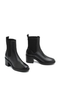 Czarne skórzane botki za kostkę z żebrowanymi tekstylnymi akcentami, okrągłym noskiem i grubym obcasem. Posiadają uchwyty do łatwego zakładania.