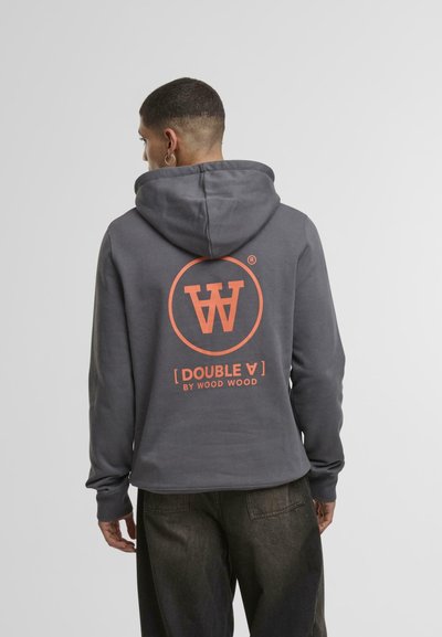 Grå hettegenser med en stor oransje sirkel-logo som har et stilisert "W" og teksten "[DOUBLE A] BY WOOD WOOD" på baksiden. Myk stofftekstur.