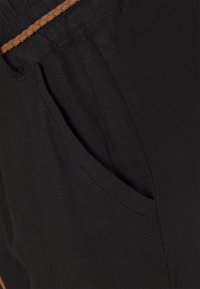 Svarta linnebyxor med en flätad brun dragsko i midjan och sidofickor, med en mjuk textur och avslappnad passform.