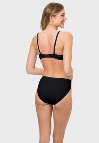 Schwarzes Lingerie-Set mit einfachem Design, verstellbaren Trägern und glattem Stoff. Hochgeschnittene Unterteile mit minimalen Details.
