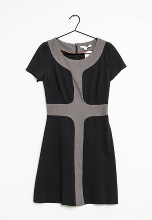 Schwarzes Kurzarmkleid mit grauem Kreuzdesign auf der Vorderseite, Rundhalsausschnitt und Reißverschluss auf der Rückseite, hängt an einem schwarzen Kleiderbügel vor einem weißen Hintergrund.