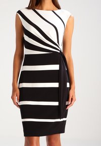 Abito a righe bianche e nere con un design frontale attorcigliato, corpetto superiore in tinta unita, maniche corte e gonna di lunghezza al ginocchio. Tessuto dalla trama liscia.