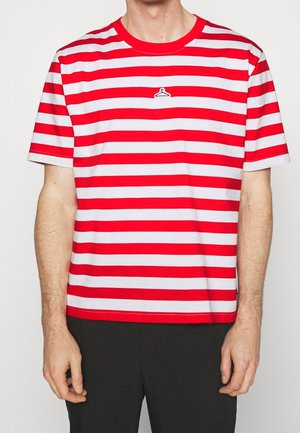 Homme portant un T-shirt à manches courtes rayé rouge et blanc avec un petit logo de cintre noir et blanc sur la poitrine.