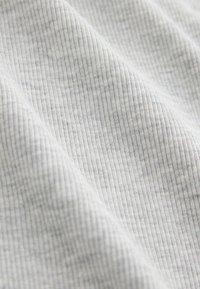 Close-up of light gray fabric with fine vertical ribbed texture and soft folds.