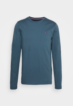 Langärmliges T-Shirt in Marineblau aus Baumwolle mit geripptem Rundhalsausschnitt und kleinem Logodetail auf der Brust. Weiche Textur und entspannte Passform.