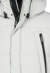 Hellgraue Steppjacke mit hohem Kragen, Frontreißverschluss und seitlichen Reißverschlusstaschen. Verfügt über eine glatte Textur mit schwarzen Metallakzenten.