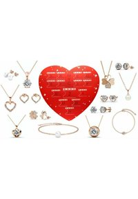 Esposizione di gioielli con collane, orecchini e braccialetti in oro rosa. Include design a cuore e a trifoglio, dettagli in cristallo e perle.