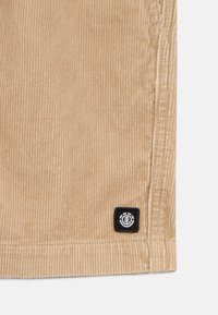 Shorts in corduroy beige con righe verticali, dotati di un'etichetta nera sull'orlo. Texture morbida e taglio classico, adatti per un abbigliamento informale.
