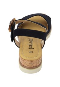 Czarny sandał z korkową podeszwą na koturnie, z dwoma regulowanymi paseczkami i zaokrąglonym noskiem. Teksturowana wkładka z elementem brandingowym.