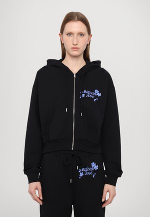 Schwarzer, kurzer Hoodie mit einem Reißverschluss auf der Vorderseite, verfügt über ein blaues Blumenlogo. Kombiniert mit schwarzen Jogginghosen, die ebenfalls dasselbe blaue Logo zeigen.