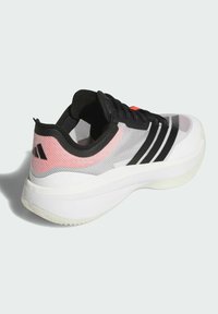 Scarpa sportiva con tomaia in mesh grigia, dettagli neri e tocchi rosa. Caratterizzata da una suola bianca spessa e lacci neri. Elementi di design distintivi.
