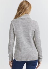 Gray knit sweater featuring a folded turtleneck, long sleeves, and ribbed hem. The texture is soft with a smooth finish.