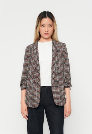 Rutete blazer i nyanser av brun og blå, med en skreddersydd passform, åpen front og oppbrettede ermer. Båret over en hvit topp.