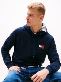 Hanorac bleumarin cu căptușeală în carouri și logo frontal. Dispune de șnur, manșete ribuate și o croială lejeră.