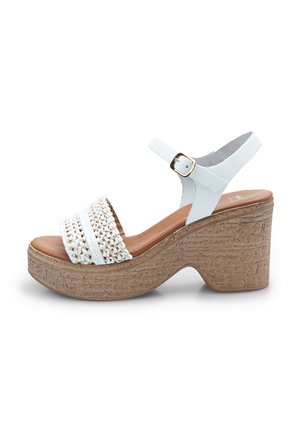 Sandales blanches avec une bride tressée, plateforme ressemblant à du liège et fermeture à boucle. Talon fermé avec une finition en cuir lisse.