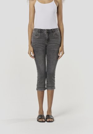 Pantacourt en denim gris avec détails de couture à l'ourlet, design à cinq poches et silhouette ajustée. Porté avec des sandales slides noires.