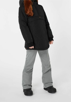 Schwarze gesteppte Jacke mit Kapuze und Fronttasche, kombiniert mit grauen Hosen und schwarzen Stiefeln. Verfügt über gerippte Bündchen und ein elegantes Design.