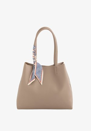 Sac cabas en cuir taupe avec de longues anses, orné d'un foulard à motif bleu et blanc noué à une anse.