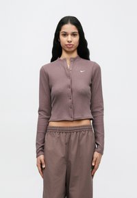 Τοπ μακρυμάνικο, ριμπ, κοντό σε χαμηλό βιολετί χρώμα με κούμπωμα με κουμπιά και μανδρινάτο γιακά, με μικρό λευκό λογότυπο στο στήθος.