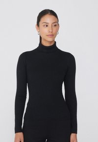 Černý žebrovaný rolák s dlouhými rukávy, přiléhavý střih a jemná textura. Minimalistický styl bez viditelných vzorů nebo akcentů.