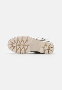 Zapato outdoor Tamaris con una suela de goma estampada, con parte superior gris y suela exterior beige claro. Materiales duraderos diseñados para ofrecer tracción.