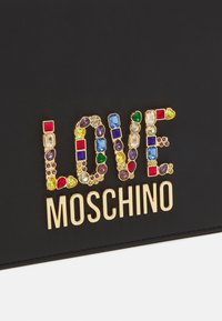 Clutch nera con la parola "LOVE" in pietre colorate simili a gemme, con "MOSCHINO" in lettering dorato in grassetto sottostante. Texture liscia.
