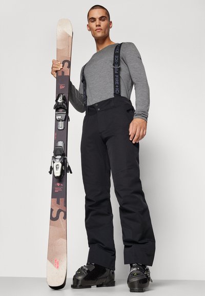 Ο εξοπλισμός σκι περιλαμβάνει γκρι μακρυμάνικο πουκάμισο, μαύρα παντελόνια σκι με αναρτήρες και μαύρες μπότες σκι. Κρατείται ένα σκι με υφή σχεδίασης.