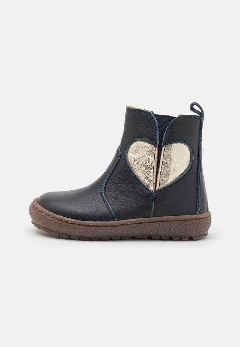 Bottine en cuir noir avec un accent cœur doré, semelle en caoutchouc marron et panneaux latéraux élastiques pour un enfilage facile. Surface texturée.