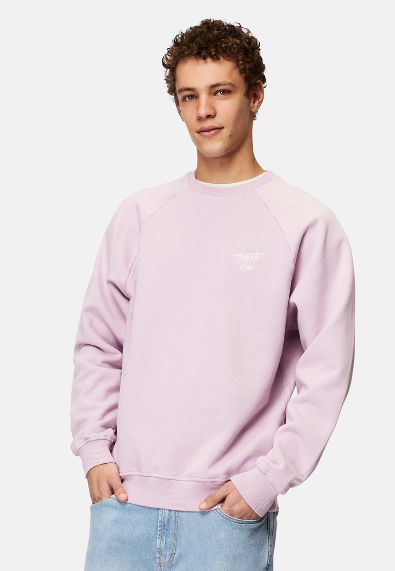 Vaaleanvioletti huppari, jossa on ribbauskaulus ja hihansuut. Rinnassa valkoinen logo. Pehmeä kangas ja löysä malli.