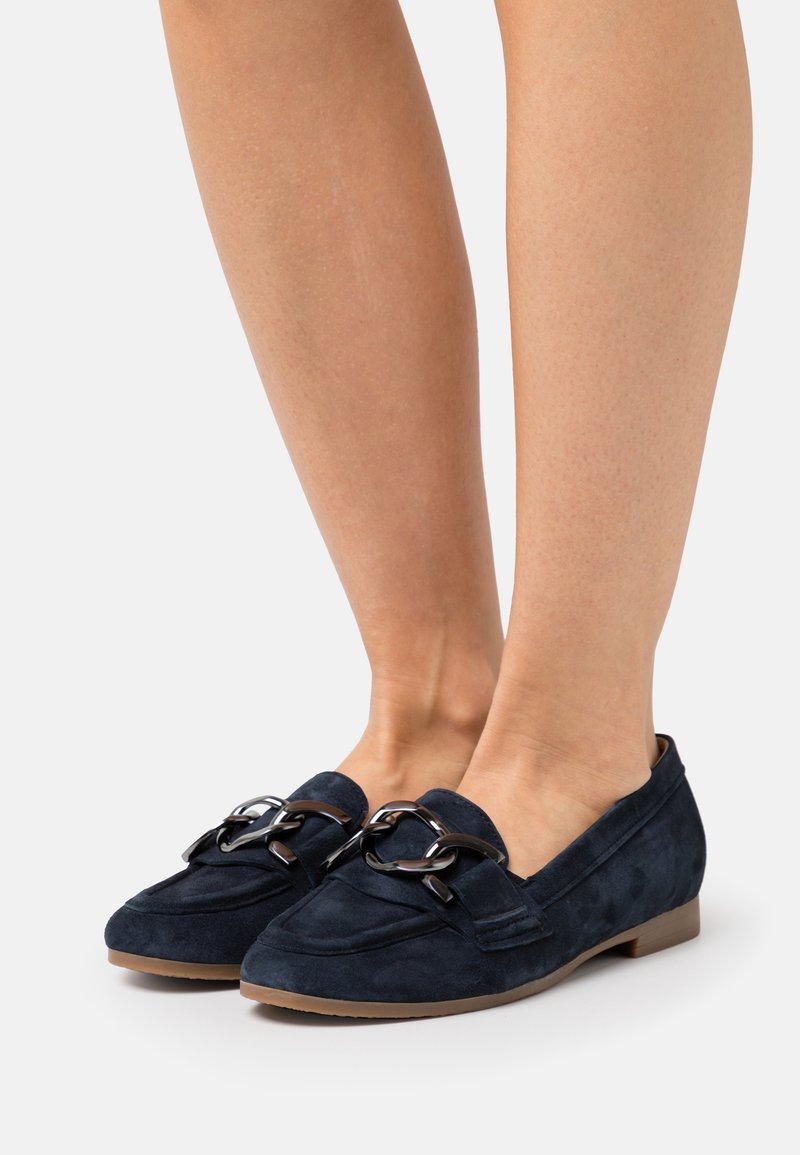Mocassins en daim bleu marine avec un bout rond, un faible talon et des accents de chaîne décoratifs sur le devant. Matériau texturé avec une finition lisse.