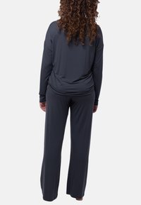 Zestaw loungewear w ciemnoszarym kolorze, składający się z luźnej, długopalcowej bluzki oraz spodni z szerokimi nogawkami, wykonany z miękkiej, gładkiej tkaniny z minimalną ilością szwów.