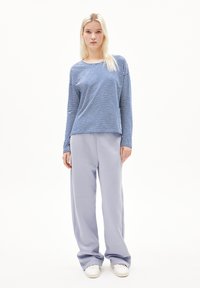 Striped long-sleeve shirt in blue and white, paired with light grey, loose-fitting sweatpants. The outfit features a relaxed design.