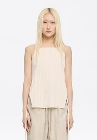 Cream, ribbed knit tank top with a square neckline and side slits. Paired with beige cargo pants featuring drawstring and large pockets.