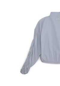 Giacca leggera grigia chiara con colletto alto, dettagli arricciati sulle maniche e orlo elasticizzato per un look aderente.