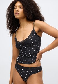 Mustast paelast top ja sobivad bikiinialused südamesemustriga, peene musta pitsi äärisega. Pehme kangas.