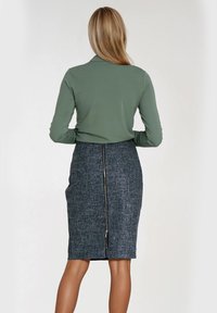 Oliwkowa bluzka z długim rękawem zestawiona z granatową spódnicą o kroju ołówkowym, posiadającą teksturowany materiał i zamek z tyłu.