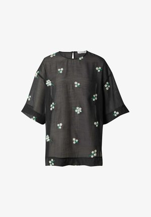Haut noir transparent à manches courtes, orné de broderies de fleurs blanches et de tiges vertes. Détail en ouverture au dos qui ajoute de l'intérêt au design.
