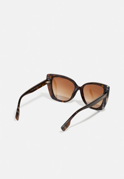 Lunettes de soleil écaille de tortue avec une forme distinctive en œil de chat, des verres bruns dégradés et des détails rayés sur les branches.