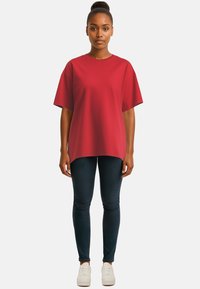T-shirt rossa over-size con maniche corte, scollatura rotonda e tessuto morbido. Abbinata a jeans skinny scuri e sneakers bianche.