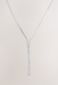 Silberne Kette mit mehreren dünnen Strängen, die eine Y-Form bilden, mit einem zentralen Knoten und quastenähnlichen Enden. Glatte, glänzende Oberfläche.