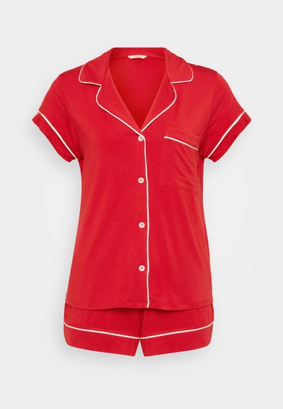 Conjunto de pijama vermelho com uma parte de cima de mangas curtas, gola em bico, detalhes brancos, fecho com botões e calções combinantes. Tecido suave, design casual.