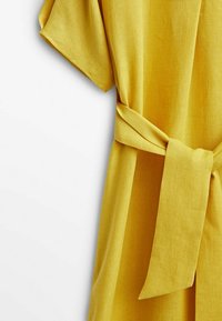 Robe en lin jaune à manches courtes, avec une taille ceinturée et une surface texturée, présentant un design simple et décontracté.