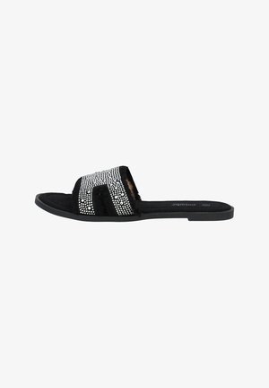 Sandale noire à enfiler avec une semelle plate, présentant une tige texturée ornée de strass en argent dans un motif en bandes.