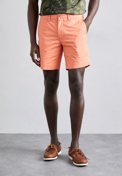 Herrliche pfirsichfarbene Baumwollshorts mit geradem Schnitt, seitlichen Taschen und Gürtelschlaufen. Getragen mit braunen Bootsschuhen.