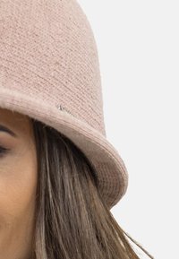 Pălărie de tip bucket tricotată roz, cu un model texturat și un mic accent metalic. Formă rotundă cu o margine ușor ridicată.